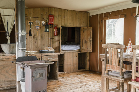 Rustic wooden lodge interior at Duynlodge, Duynpark Het Zwanenwater, Netherlands, with stove and table.