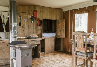 Rustic wooden lodge interior at Duynlodge, Duynpark Het Zwanenwater, Netherlands, with stove and table.