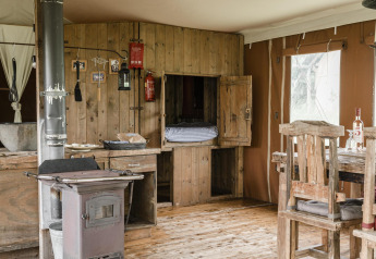 Interno rustico in legno di Duynlodge, Duynpark Het Zwanenwater, Paesi Bassi, con stufa e tavolo.