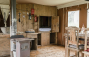 Rustic wooden lodge interior at Duynlodge, Duynpark Het Zwanenwater, Netherlands, with stove and table.