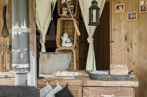Rustic kitchen scene with wooden counter, metal sink, utensils and lantern at Duynlodge, Duynpark Het Zwanenwater.