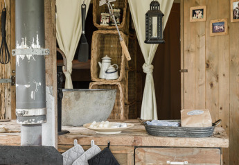 Rustic kitchen scene with wooden counter, metal sink, utensils and lantern at Duynlodge, Duynpark Het Zwanenwater.