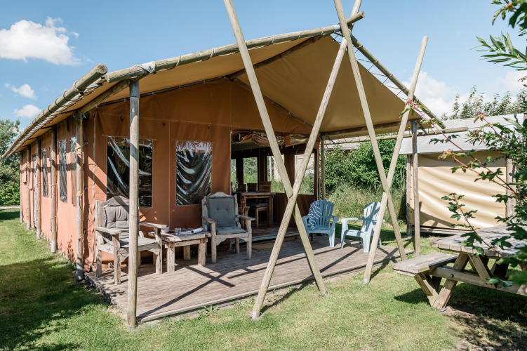 Alojamiento tipo lodge con terraza cubierta y muebles de madera en Duynlodge, Duynpark Het Zwanenwater, Países Bajos.