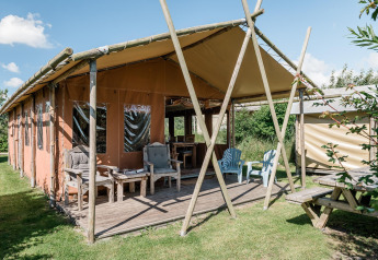 Lodge mit überdachter Veranda, Holzmöbeln und grüner Umgebung bei Duynlodge im Duynpark Het Zwanenwater, Niederlande.