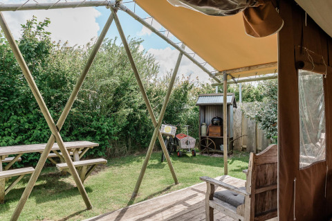 Udsigt fra en hytte ved Duynlodge i Duynpark Het Zwanenwater, Holland, med bænk, bord og grøn have.