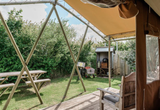 Udsigt fra en hytte ved Duynlodge i Duynpark Het Zwanenwater, Holland, med bænk, bord og grøn have.