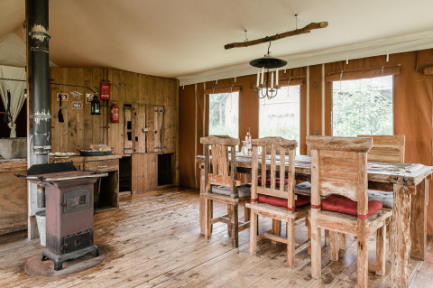 Interior de lodge rústico en Duynlodge, Duynpark Het Zwanenwater, Países Bajos, con muebles de madera y estufa.