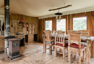 Interior de lodge rústico en Duynlodge, Duynpark Het Zwanenwater, Países Bajos, con muebles de madera y estufa.