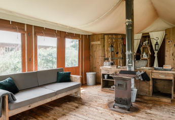 Interior de la tienda safari Duynlodge con estufa de leña y muebles rústicos en Duynpark Het Zwanenwater, Países Bajos.