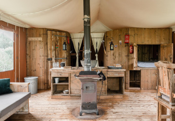 Rustikale Lodge-Innenansicht in Duynlodge, Duynpark Het Zwanenwater, Niederlande, mit Holz, Ofen und Möbeln.