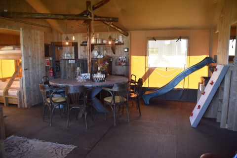 Intérieur du Kidz Lodge à Duynpark Het Zwanenwater, Pays-Bas, avec toboggan, lits superposés et table.