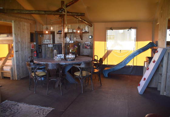 Interior de Kidz Lodge en Duynpark Het Zwanenwater, Países Bajos, con tobogán, literas y comedor.