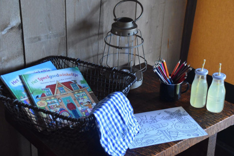 Mesa con libros para colorear, lápices de colores, linterna y jugos en Kidz Lodge, Duynpark Het Zwanenwater.