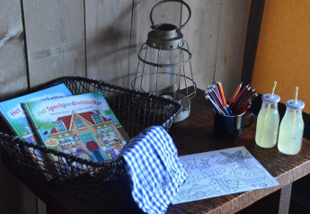 Table with coloring books, colored pencils, lantern, socks, and juice bottles at Kidz Lodge, Duynpark Het Zwanenwater.