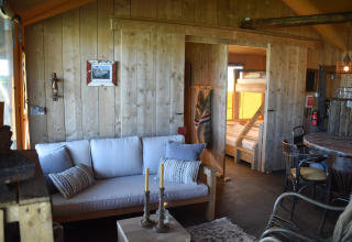 Salon chaleureux en bois du Kidz Lodge à Duynpark Het Zwanenwater, Pays-Bas, avec canapé et lits superposés.