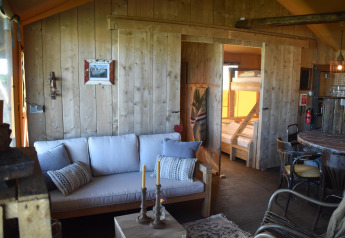 Interno accogliente in legno della Kidz Lodge al Duynpark Het Zwanenwater, Paesi Bassi, con divano e letti a castello.