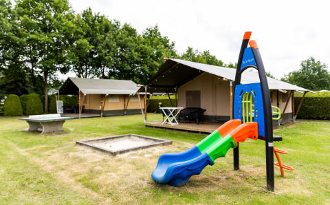 Safari-Zelt bei De Tien Heugten in den Niederlanden mit Spielplatz und Rutsche auf einer Wiese.