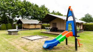 Safari-Zelt bei De Tien Heugten in den Niederlanden mit Spielplatz und Rutsche auf einer Wiese.