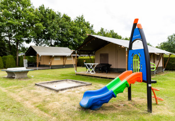 Safari-Zelt bei De Tien Heugten in den Niederlanden mit Spielplatz und Rutsche auf einer Wiese.