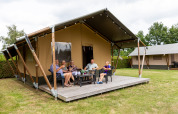 Eine Gruppe Menschen entspannt sich auf der Veranda eines Safarizelts bei De Tien Heugten, Niederlande.