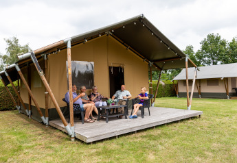 Eine Gruppe Menschen entspannt sich auf der Veranda eines Safarizelts bei De Tien Heugten, Niederlande.