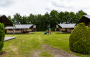 Safari-telt på De Tien Heugten, Holland, med grønne plæner, legeplads og telte omgivet af træer.