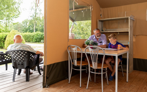 Escena interior y exterior en una tienda safari en De Tien Heugten, hombres mayores y un niño de vacaciones en Holanda.