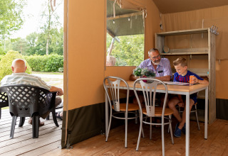 Innen- und Außenszene in einem Safarizelt mit älteren Männern und einem Jungen, entspannter Urlaub in Holland.