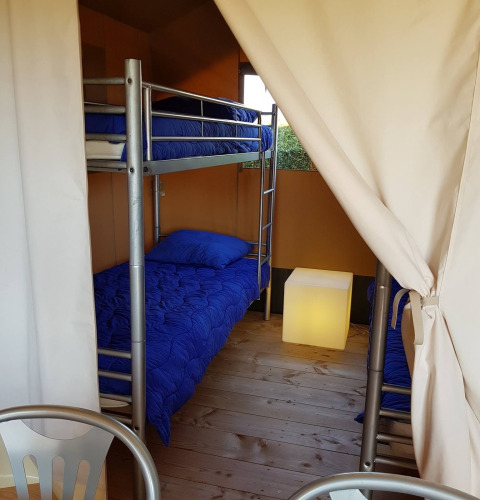 Innenraum eines Safarizelts bei De Tien Heugten in den Niederlanden mit Etagenbetten und blauer Bettwäsche.