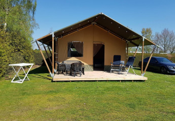 Safari telt på De Tien Heugten i Holland, med terrasse, havemøbler og parkeret bil på en solrig dag.