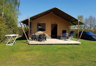 Safari-Zelt bei De Tien Heugten in den Niederlanden mit Terrasse, Gartenmöbeln und Auto auf Rasen.