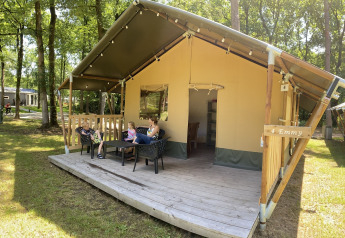 Familie slapper af foran safariteltet Safari tent på Holiday Park Bonte Vlucht i Holland om sommeren.