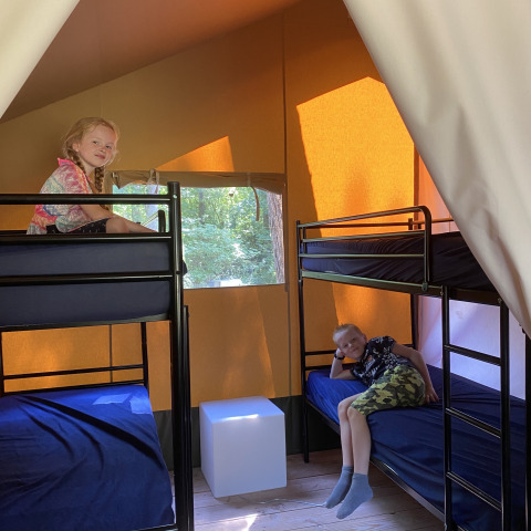 Due bambini si rilassano sui letti a castello in una tenda safari all'Holiday Park Bonte Vlucht, Paesi Bassi.