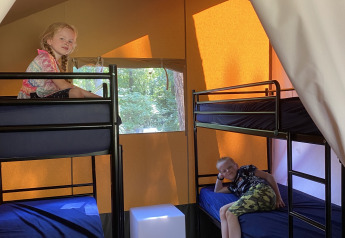 Due bambini si rilassano sui letti a castello in una tenda safari all'Holiday Park Bonte Vlucht, Paesi Bassi.