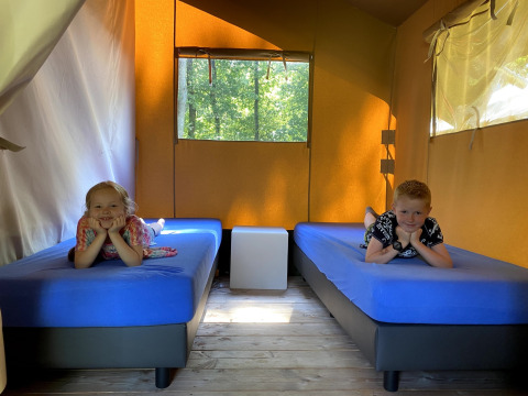 Zwei Kinder liegen auf Einzelbetten in einem Safarizelt im Holiday Park Bonte Vlucht, Niederlande.