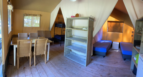 Interior de una tienda safari en Holiday Park Bonte Vlucht, Países Bajos, con mesa comedor y camas visibles.