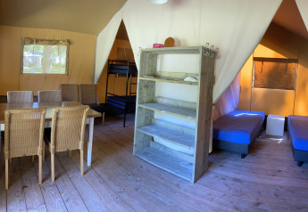Interno di una tenda safari a Holiday Park Bonte Vlucht, Paesi Bassi, con tavolo da pranzo e letti.