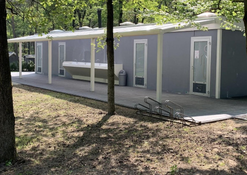Udendørs toiletbygning ved Safari-teltet i Holiday Park Bonte Vlucht i Holland, omgivet af træer.