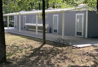Servizi igienici all'aperto vicino alla tenda safari di Holiday Park Bonte Vlucht nei Paesi Bassi, tra alberi.