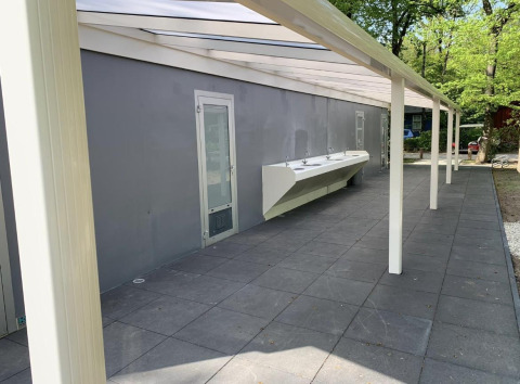Stazione di lavaggio esterna presso una tenda safari a Holiday Park Bonte Vlucht, Paesi Bassi, tra alberi.