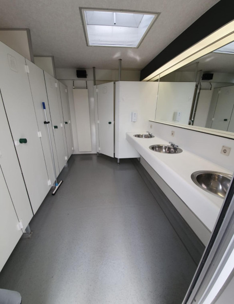 Foto di un bagno pulito e moderno con lavandini, specchi e cabine in una tenda safari di un parco olandese.