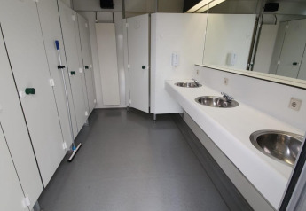 Foto di un bagno pulito e moderno con lavandini, specchi e cabine in una tenda safari di un parco olandese.