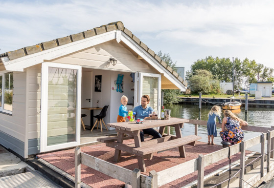 Familie hygger sig udenfor en chalet ved Marina Parcs Almere, med udsigt over vandet i Holland.