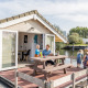 Familie hygger sig udenfor en chalet ved Marina Parcs Almere, med udsigt over vandet i Holland.