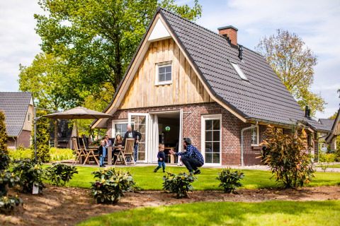 Familia disfrutando al aire libre en una tiny house Wellness Lodge XL en Hof van Salland, Países Bajos.