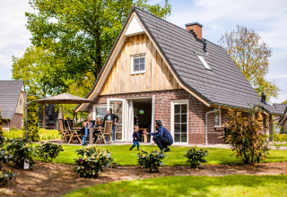 Familia disfrutando al aire libre en una tiny house Wellness Lodge XL en Hof van Salland, Países Bajos.
