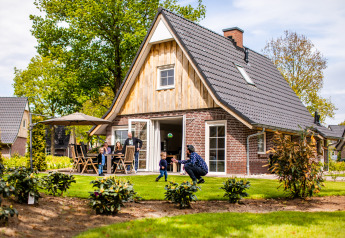 Familia disfrutando al aire libre en una tiny house Wellness Lodge XL en Hof van Salland, Países Bajos.