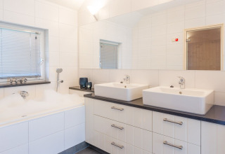 Baño moderno en Wellness Lodge XL con lavabo doble, bañera y azulejos blancos grandes en Hof van Salland.