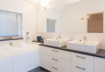 Bagno moderno nella Wellness Lodge XL con doppio lavabo, vasca e grandi piastrelle bianche a Hof van Salland.