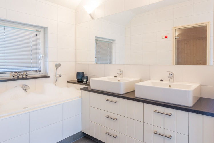 Moderne badkamer in Wellness Lodge XL met dubbele wastafel, ligbad en witte tegels bij Hof van Salland.